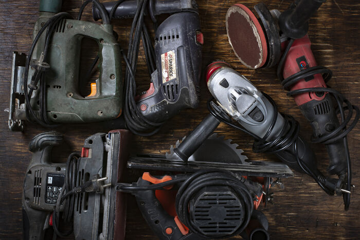 Various power tools laid out, highlighting left-handed people struggles due to design favoring right-handed use.