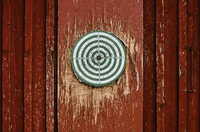 A dartboard on a wooden wall, representing left-handed people struggles with typical right-handed designs.