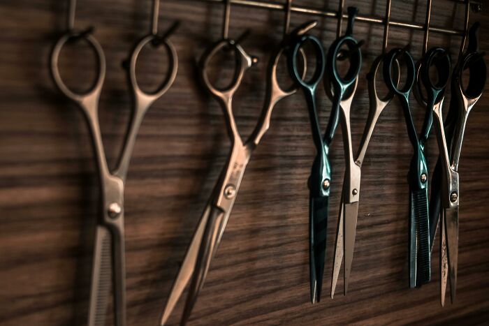 Scissors hanging on a rack, highlighting left-handed people struggles with using right-handed tools.