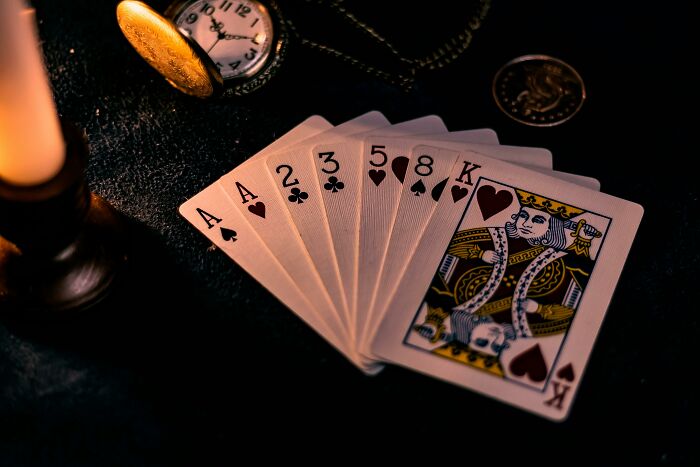 Playing cards fan out on a table with vintage watch and coin, symbolizing left-handed people struggles with everyday items.