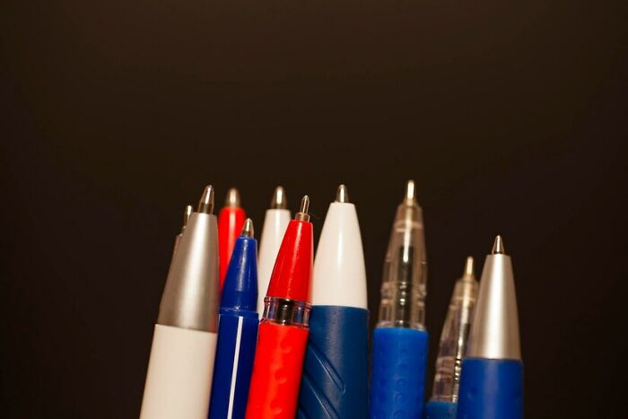 Assorted pens with grips, highlighting left-handed struggles with writing tools.