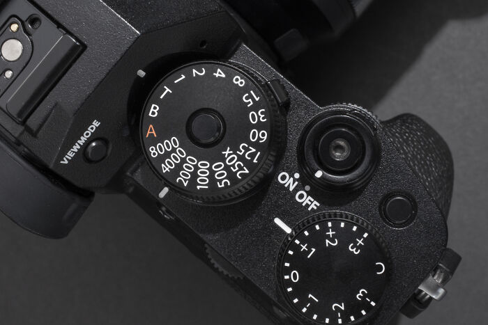 Close-up of a camera top view highlighting dials, showcasing left-handed-people struggles with right-handed designs.