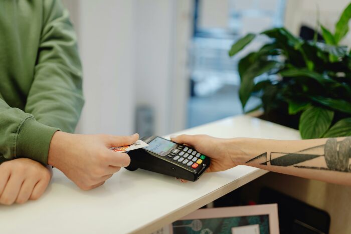 Left-handed person using a card reader in a store, highlighting left-handed struggles with technology.