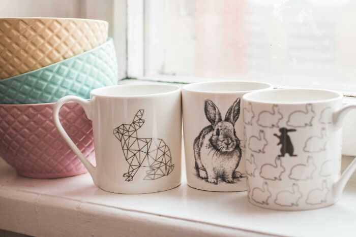 Mugs with rabbit designs on a windowsill, next to pastel bowls, left-handed-people-struggles with daily tasks.