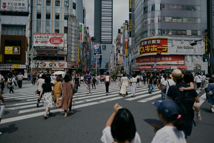 Busy crosswalk in a city with people wearing casual clothes, highlighting everyday norms.