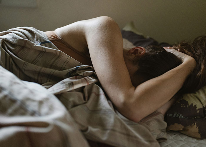 Person lying in bed, arms over head, reflecting on life-changing events.