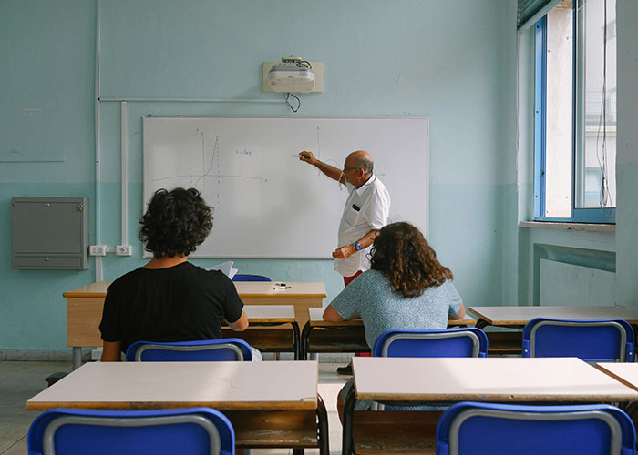 Teacher explaining a graph on a whiteboard to students, illustrating a life-changing educational event.