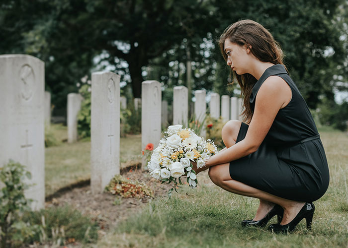 Woman kneeling with flowers at a cemetery, reflecting on a life-changing event.