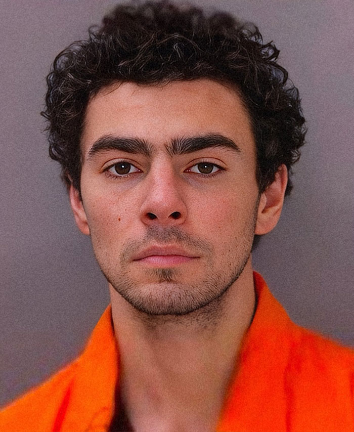 Luigi Mangione mugshot in an orange shirt with curly hair, appearing serious.