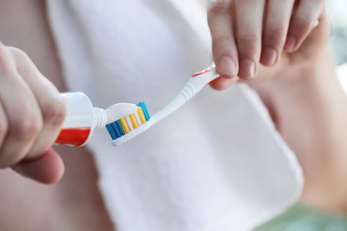 Person applying toothpaste to a toothbrush, related to cringeworthy travel situations.