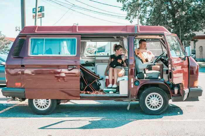 Fun jobs: Two people sitting in a parked, classic red van, relaxing in a casual setting.