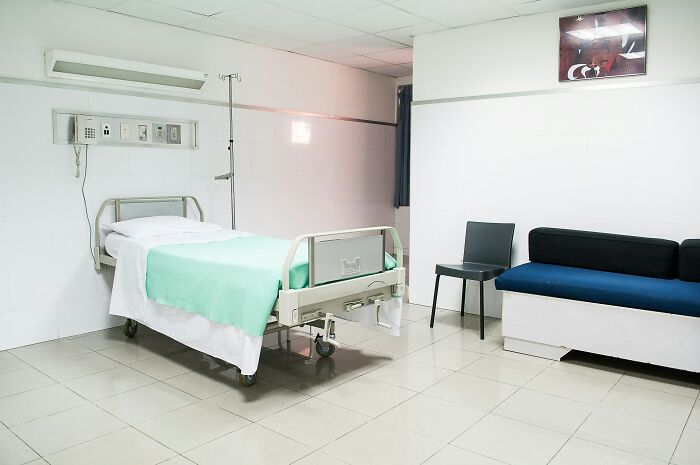 Hospital room with a single bed, green blanket, and medical equipment, symbolizing survival against all odds.