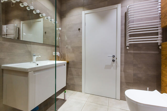 Modern bathroom with a glass sink and tiled walls, showcasing an awkward travel moment for visitors.