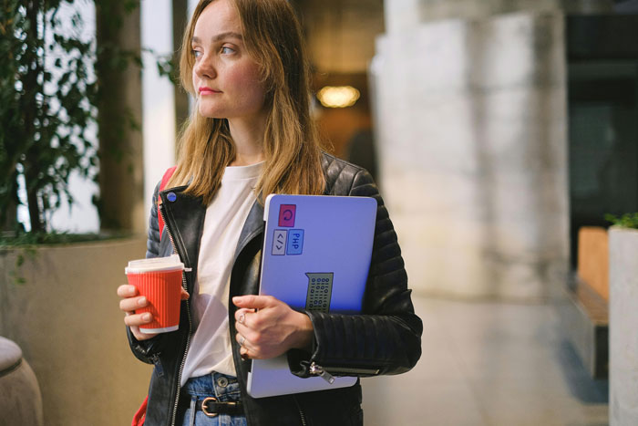 Woman holding a coffee cup and a laptop, representing mom-relationship-drama in a modern setting.