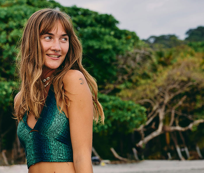 Woman smiling outdoors, wearing a green top, represents "born gifted" theme in a natural setting.