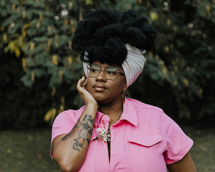 Person in a pink shirt and glasses, expressing contemplation, illustrating born gifted stereotypes and misconceptions.