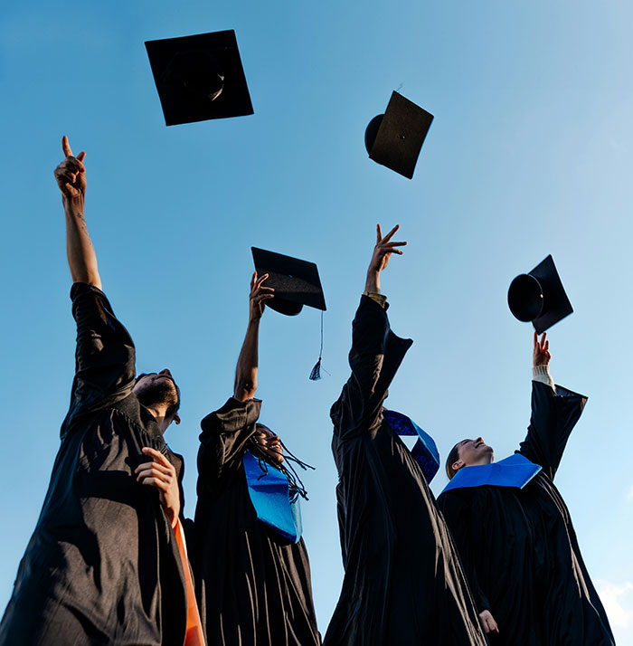 Graduates celebrating by throwing caps in the air, challenging stereotypes and misconceptions about being born gifted.