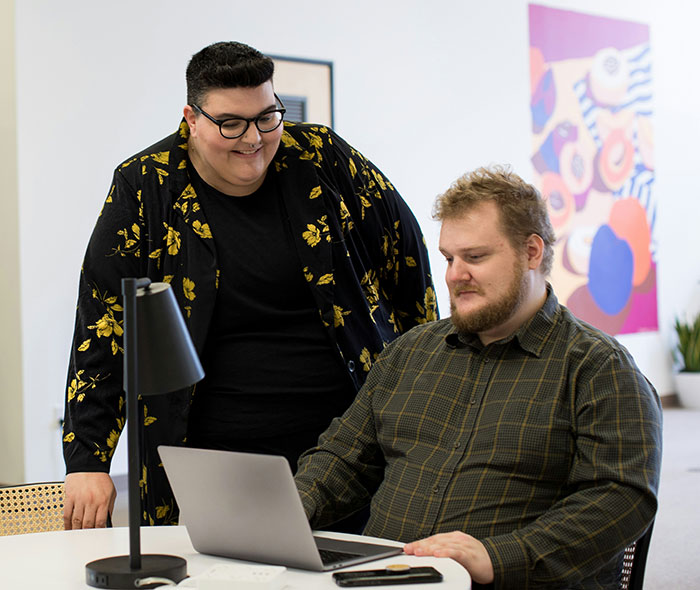 Two people engaging at a laptop, discussing misconceptions about giftedness while in a modern office setting.