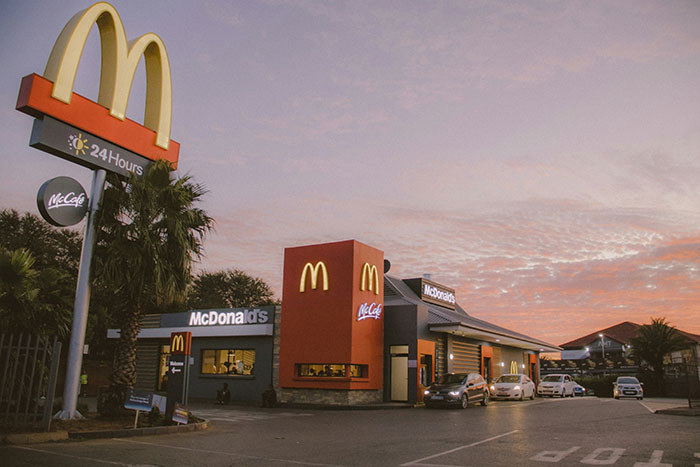 McDonald's restaurant exterior at sunset, highlighting 24-hour service and McCafe signage.