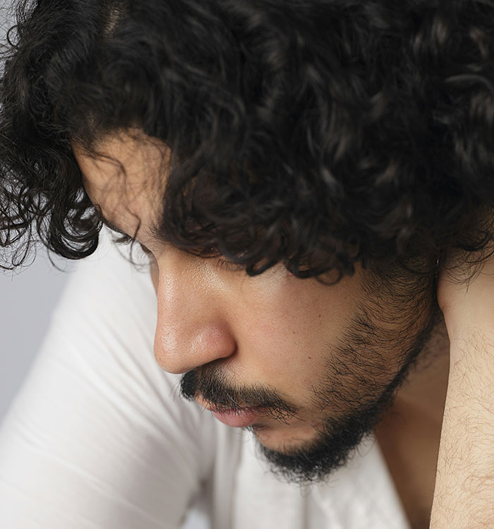 A person with curly hair reflects pensively, highlighting misconceptions about being born gifted.