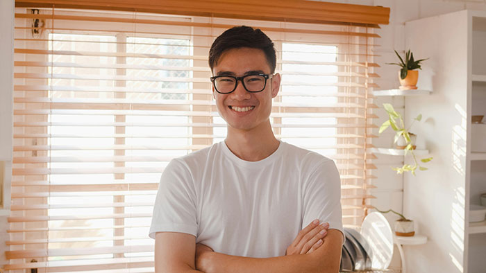 Smiling man in casual wear standing confidently in a bright room, challenging gifted stereotypes.