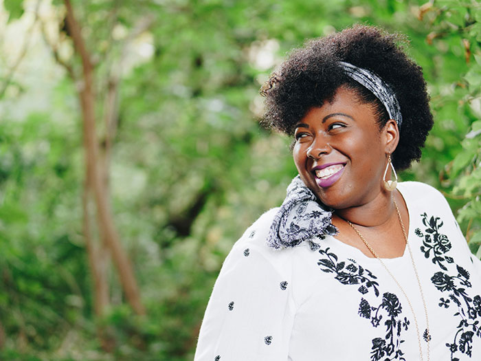 Person smiling in a floral top, representing the joy of debunking stereotypes and misconceptions about being "born gifted."