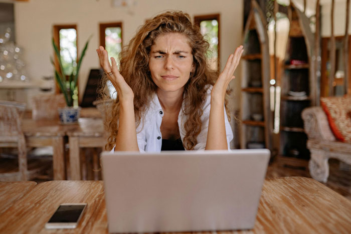 Mother looking frustrated at laptop, symbolizing money and family emergency concerns at home.