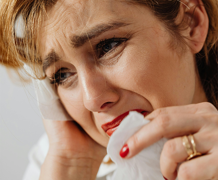 Upset mother wiping tears with a tissue, emotional over wedding song decision.