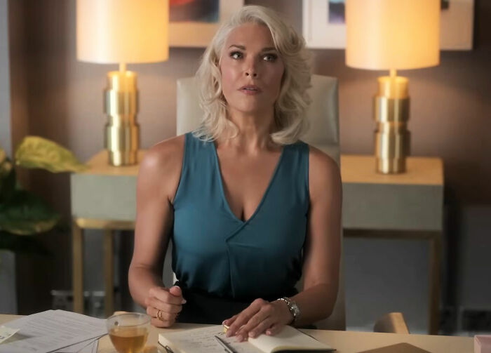 Woman in an office setting, reflecting on movies' portrayal of women, with a journal and tea on the desk.