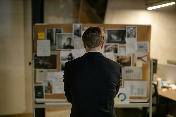 A person in a suit studies a bulletin board with photos and notes, symbolizing the flawed portrayal of women in movies.