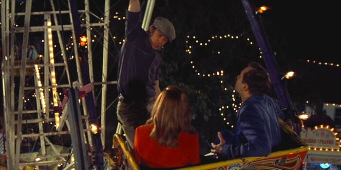 A person hangs from a Ferris wheel near a couple, highlighting movies' poor portrayal of women.