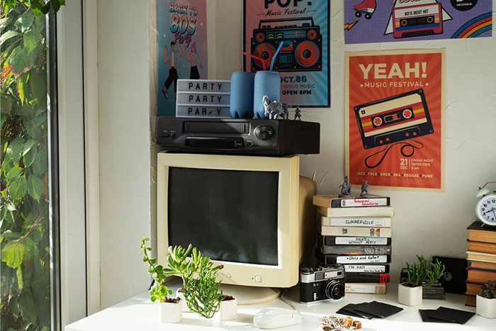 Vintage computer and cassette player on a desk with 80s music posters, depicting things that used to be obvious.