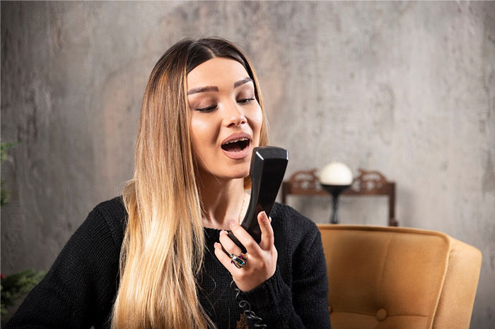 Woman using a vintage phone, illustrating things that confuse people now but were obvious 15 years ago.