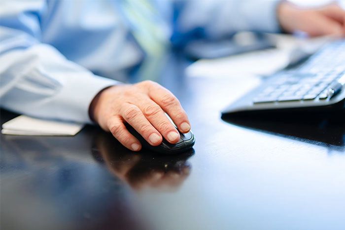 Hand using a computer mouse at an office desk, illustrating technology changes over time.