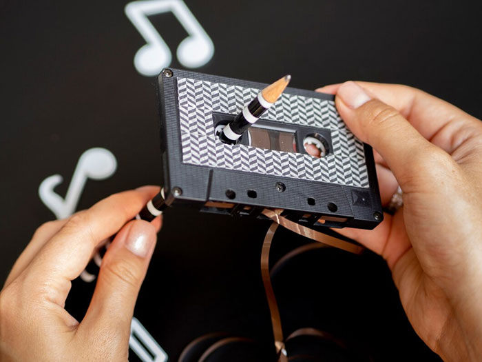 Hands holding a cassette tape with a pencil, symbolizing confusion over once obvious technology.