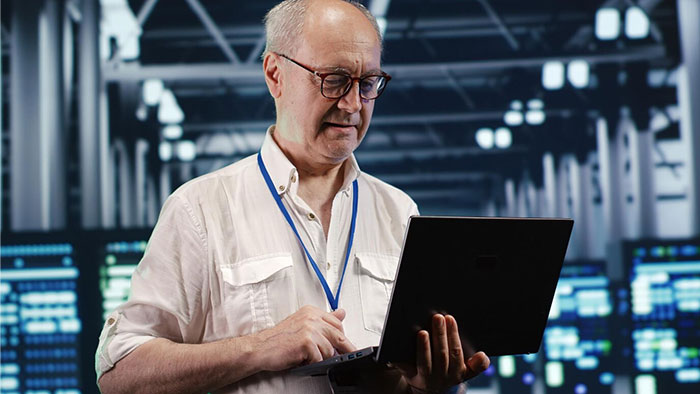 Man in a data center holding a laptop, reflecting on what was once obvious but is now confusing for some.