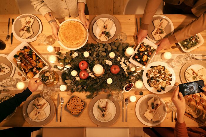 Old parents and children gather around a Christmas dinner table with festive decorations and a variety of holiday dishes.