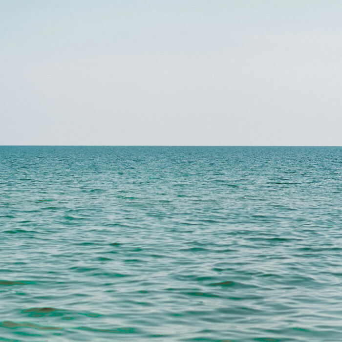 A vast ocean with a clear horizon under a bright sky, evoking a moment of realization.