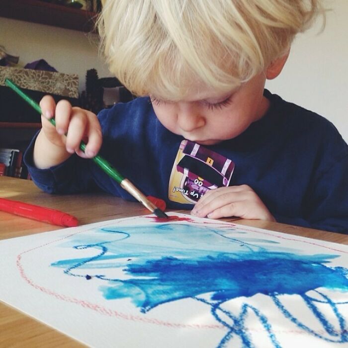 Young child engaged in a creative painting activity, demonstrating parenting genius tricks in art development.