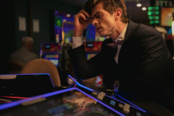 Casino employee focused on slot machines in a dimly lit casino environment.