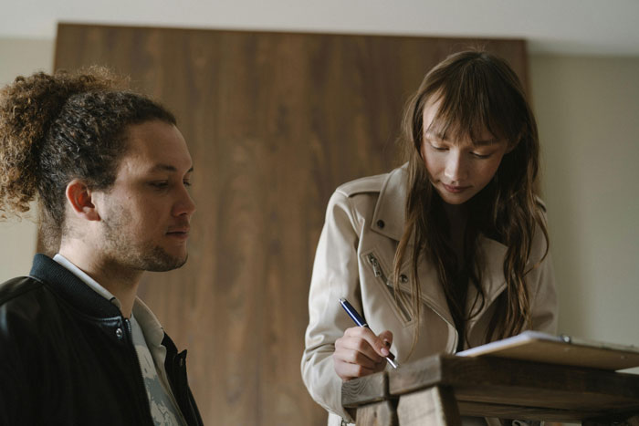 A couple, one writing on a clipboard, the other listening intently.