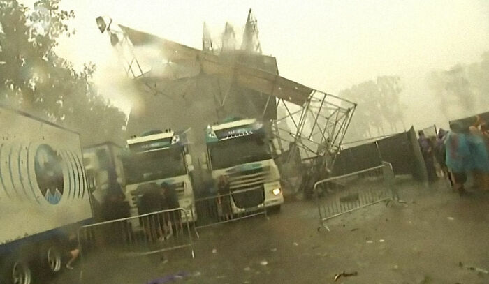 Severe storm aftermath with collapsed stage and trucks at a festival, illustrating incredibly lucky survival amidst chaos.