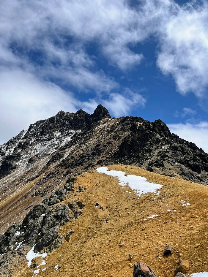 Snow-dusted mountain peak under a blue sky, illustrating lucky survival in harsh conditions.