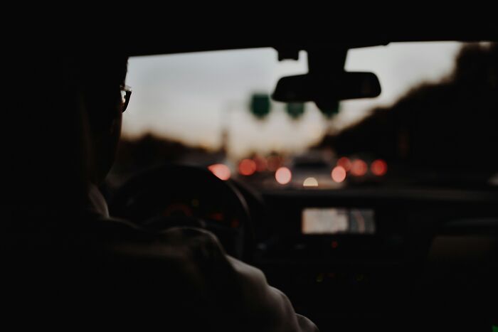 Silhouette of a driver on a busy road at dusk, illustrating survival against all odds in low-light conditions.