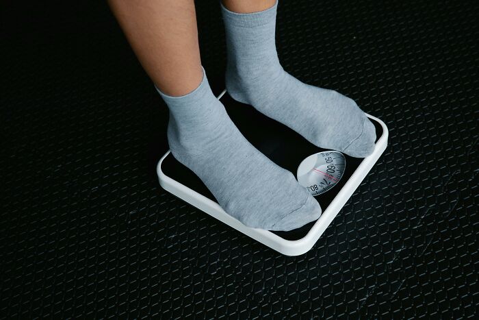 Person standing on a bathroom scale with gray socks, highlighting survival against all odds.