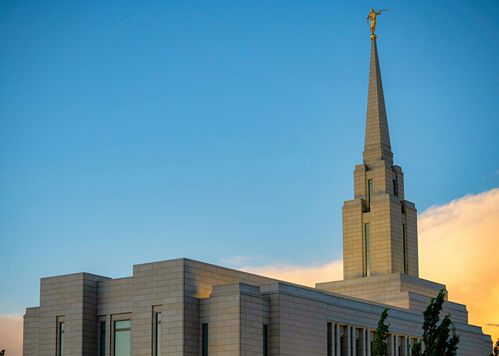 Mormon temple with golden spire at sunset, showcasing architectural beauty and spiritual significance.