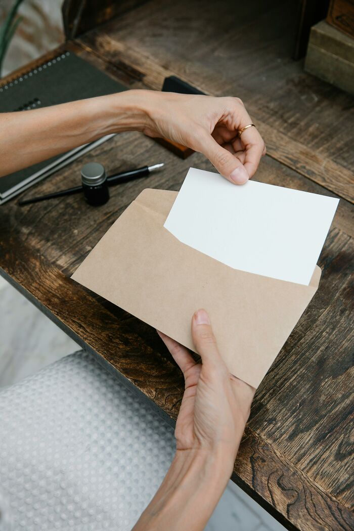 Hands holding a blank card and envelope, possibly conveying secrets to a loved one.