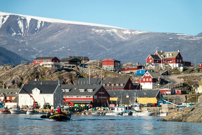 Scenic coastal village against a mountainous backdrop showing historical influence on local architecture.