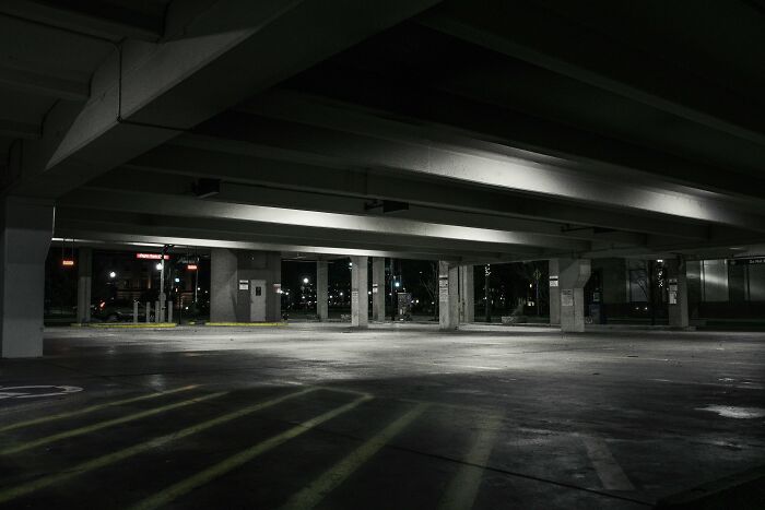 Dimly lit, empty parking garage suggesting unexpected encounters.