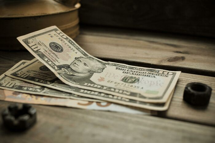 Close-up of various US dollar bills on a wooden table, depicting rare everyday facts about currency.